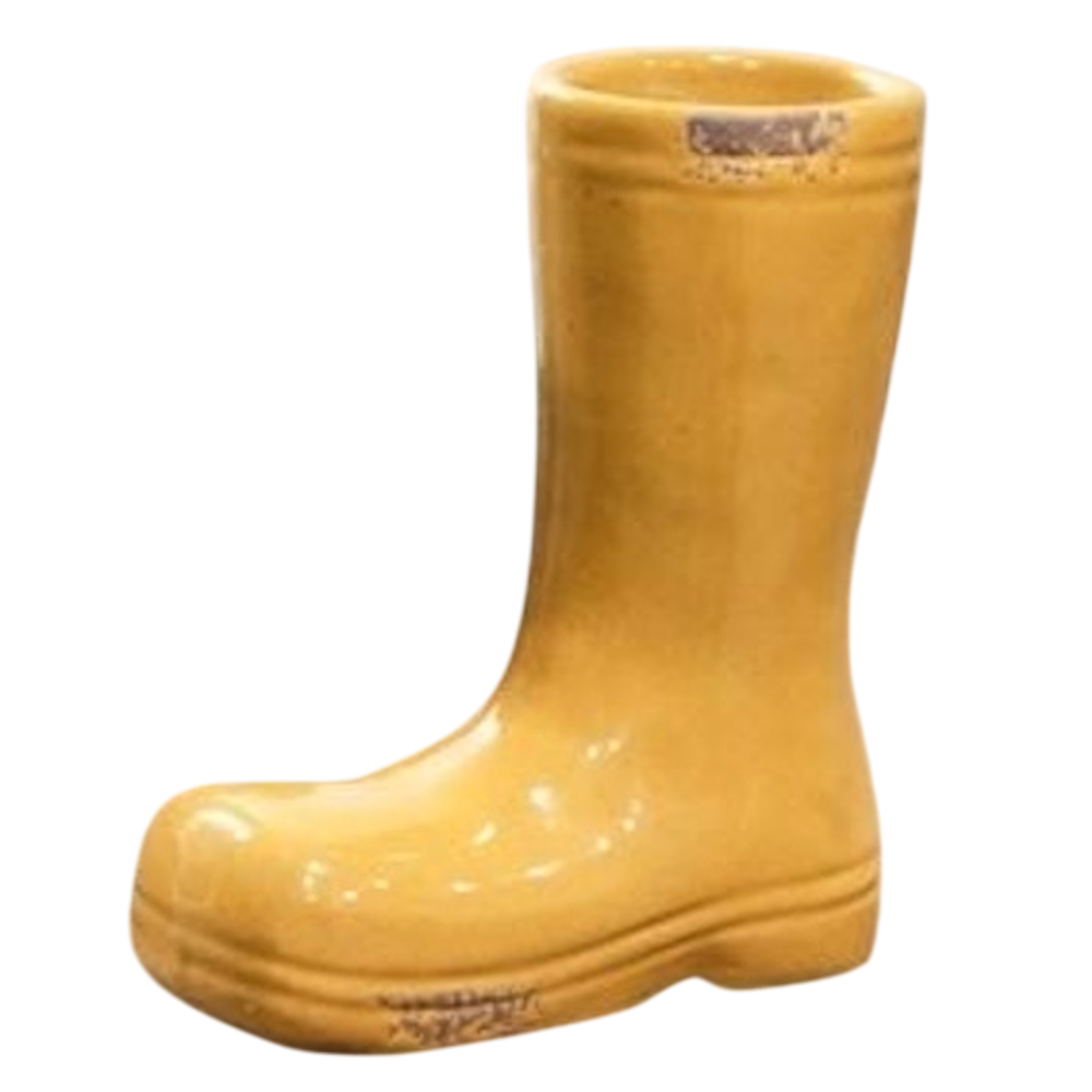 A glossy, mustard-yellow ceramic planter shaped like a miniature rain boot on a white background.