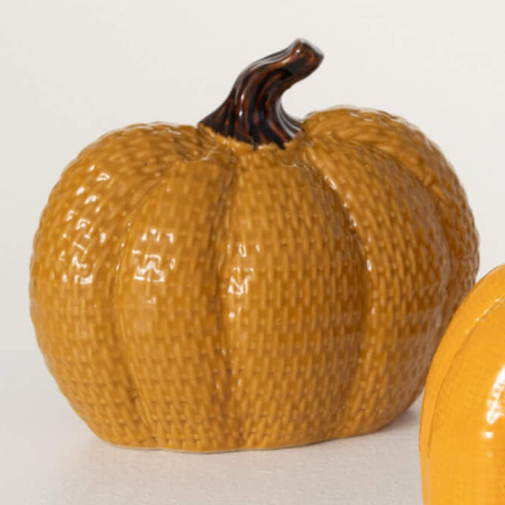 A textured mustard yellow ceramic pumpkin decorative object with a brown stem.