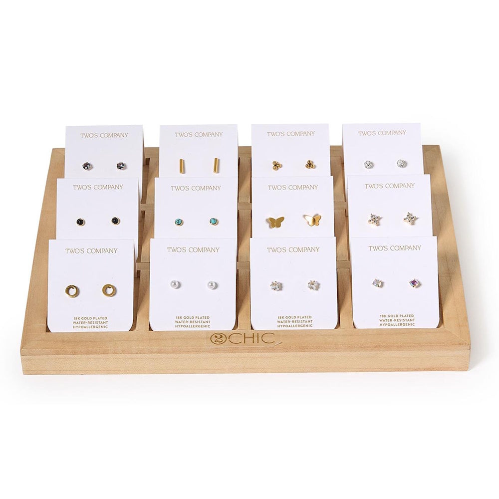 Wooden display tray showcasing twelve pairs of small stud earrings mounted on white card backings.